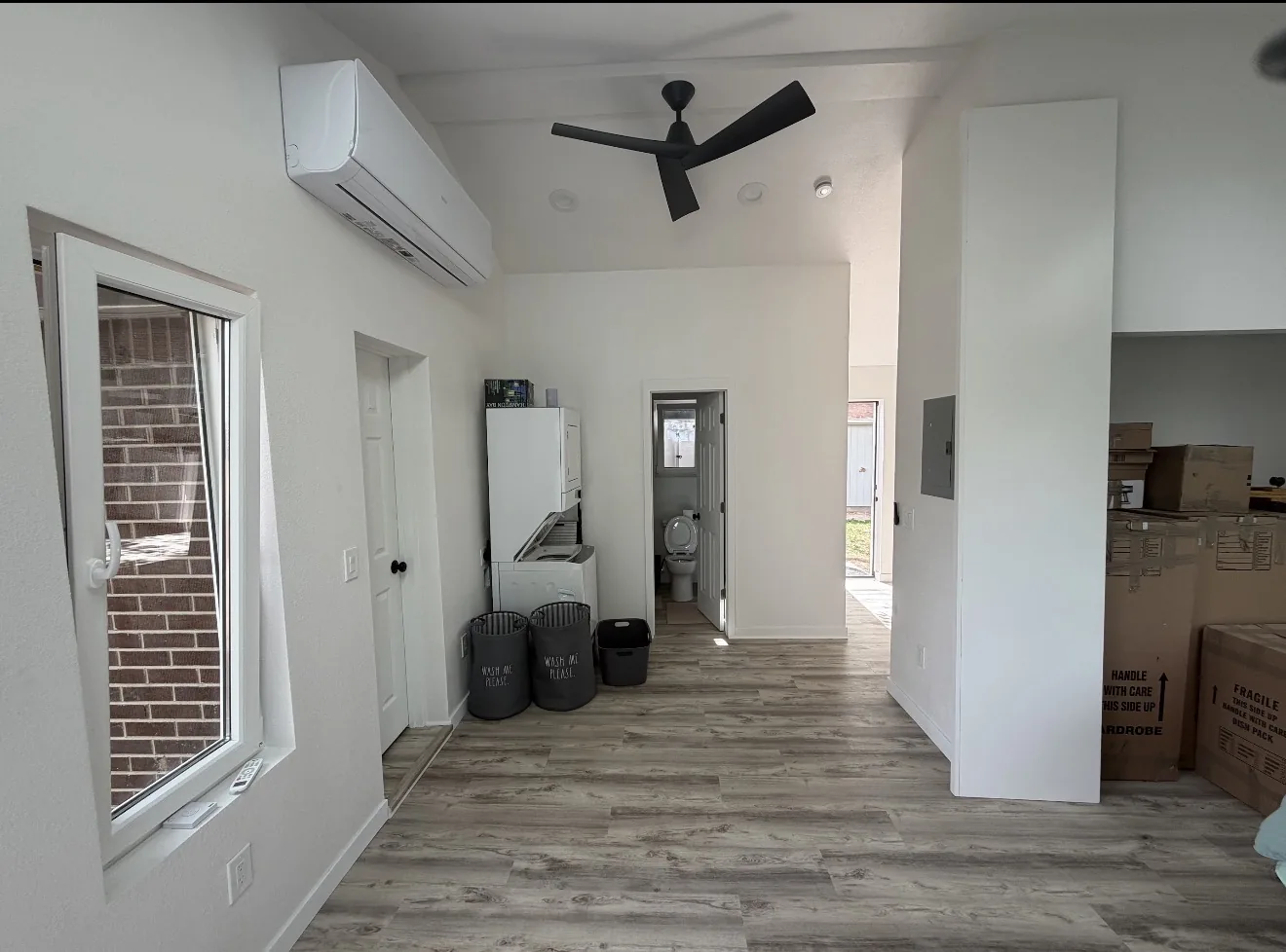 Main interior living area with laundry, bathroom access, window, and mini-split