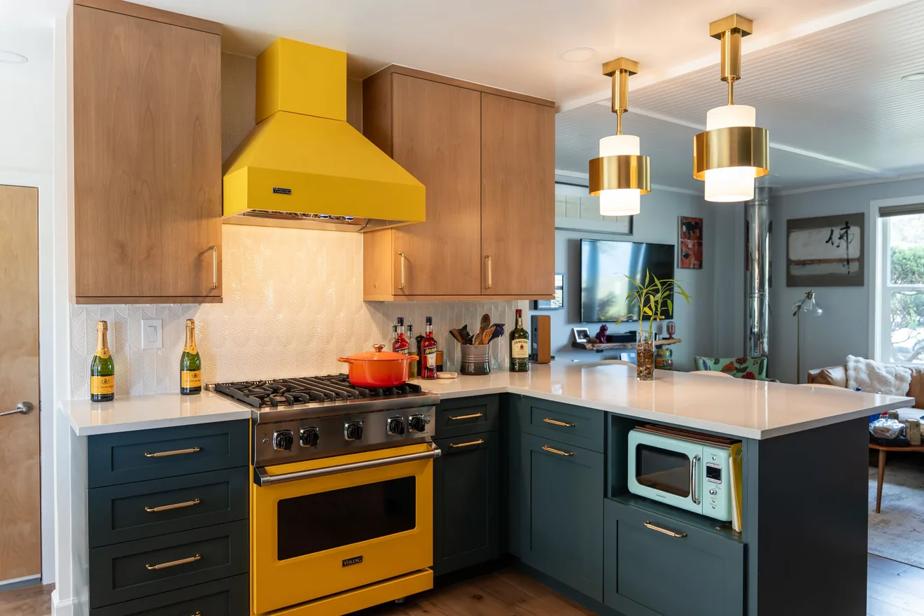 Updated kitchen with blue cabinets, wood cabinetry, yellow range, and bright finishes
