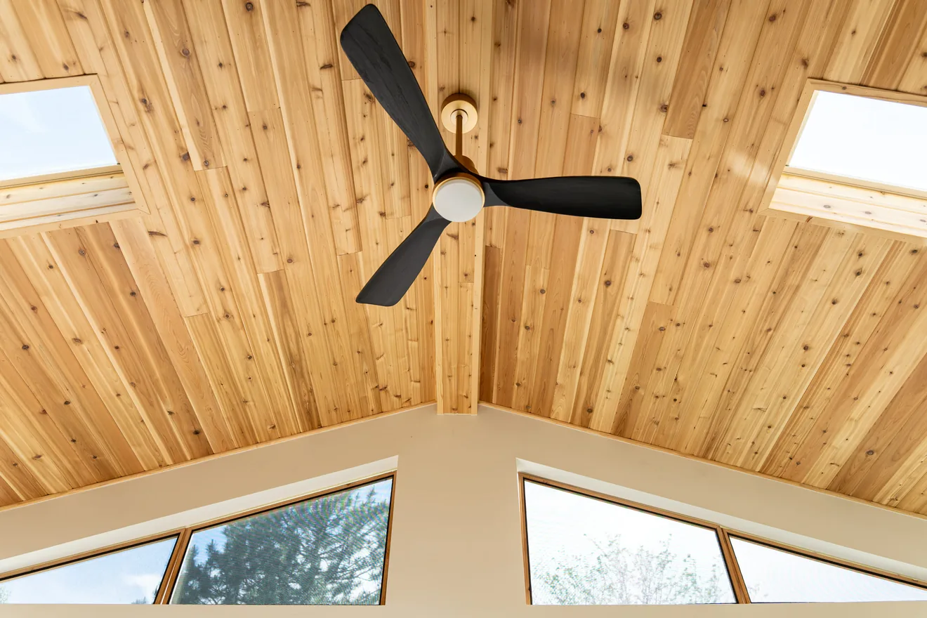 Vaulted wood ceiling with skylights and ceiling fan inside the custom sunroom
