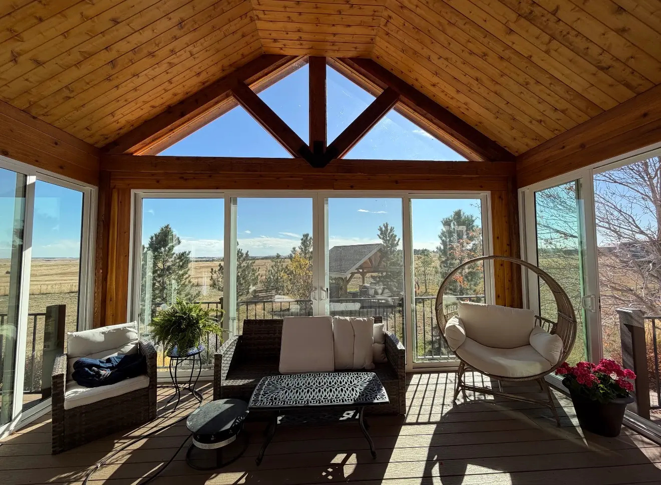 Interior view of elevated sunroom with cedar ceiling and panoramic glass in Elizabeth, Colorado