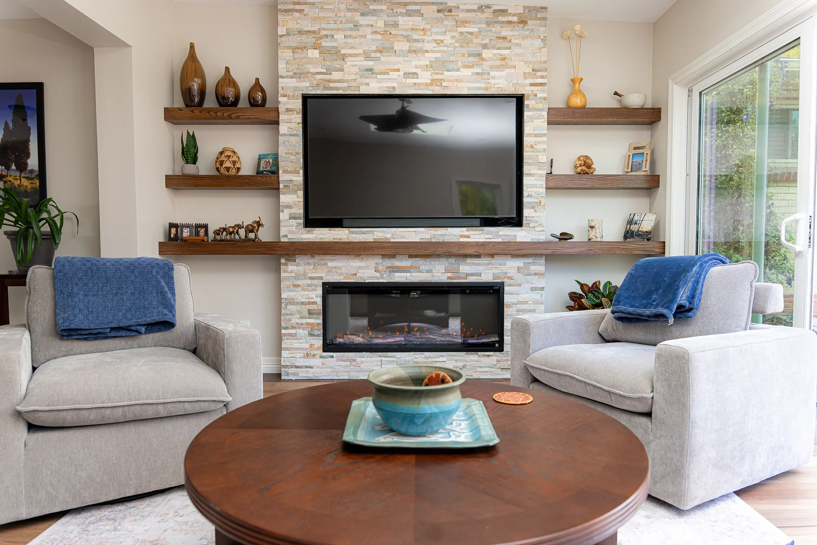 Finished sunroom seating area with a stone fireplace wall and television