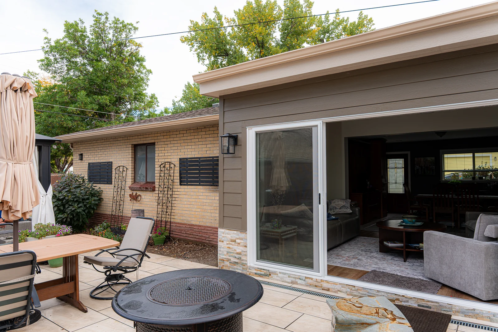 View across the paved patio toward the new sunroom and existing home