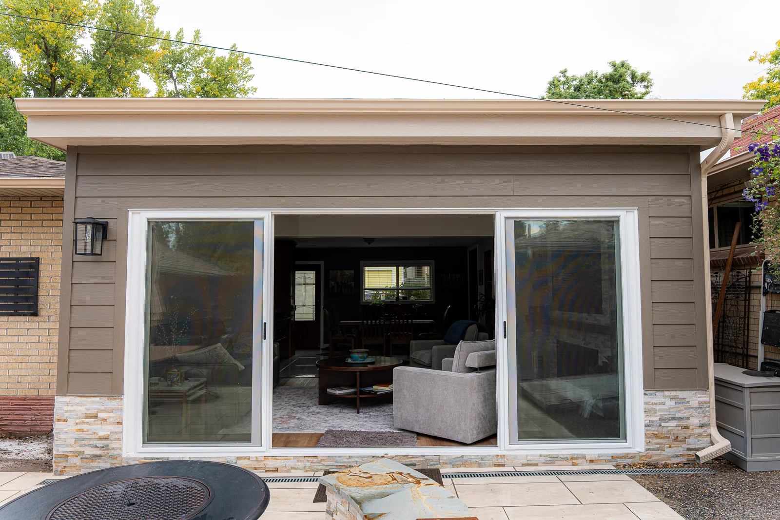 Four-panel sliding glass door open to the paved backyard patio
