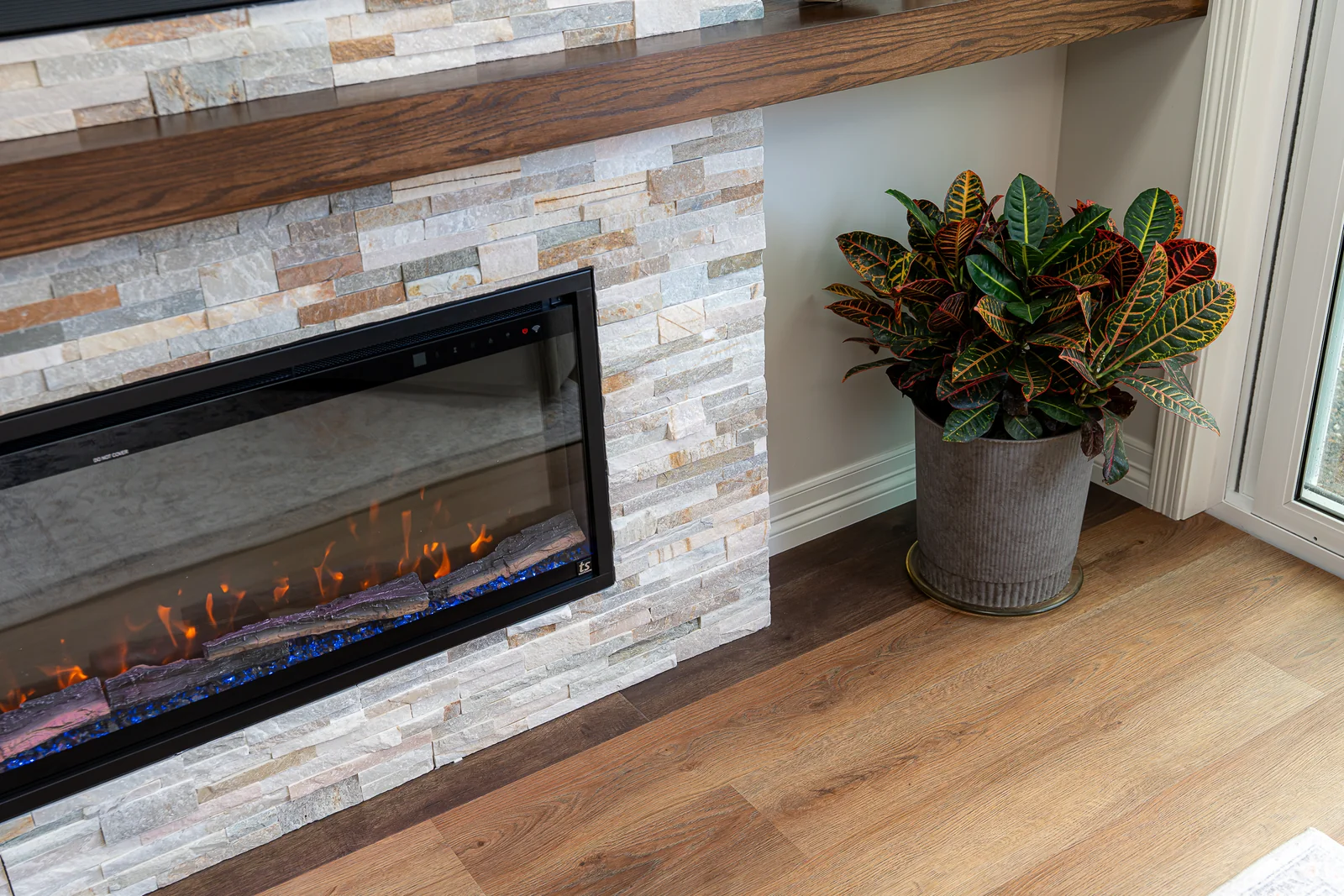 Close view of the fireplace, stone wall finish and engineered flooring